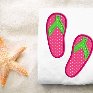 Op de afbeelding: Een witte handdoek met twee geborduurde flip-flop designs in roze en groen. De flip-flops hebben witte stippen.
