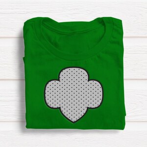 May include: A green t-shirt with a white and black dotted Girl Scout cookie logo.