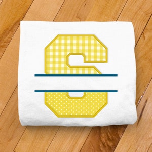 Puede incluir: Una camiseta blanca con un número amarillo "6" en un patrón de cuadros. El número está dividido por la mitad con una línea azul, lo que permite agregar un nombre.