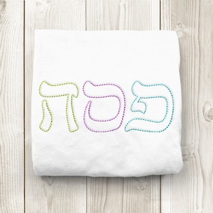 May include: White fabric with the Hebrew word "Shabbat" embroidered in green, purple, and blue thread.