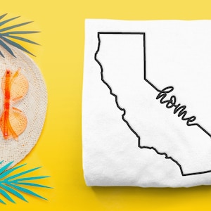 Puede incluir: Camiseta blanca con un contorno negro del estado de California y la palabra "home" escrita en cursiva.