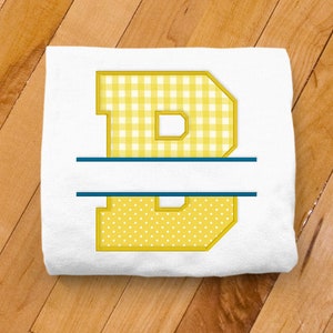 May include: White t-shirt with a yellow letter "B" in a gingham and polka dot pattern. The letter is split in half with a blue line.