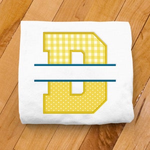 May include: A white t-shirt with a yellow letter "D" split in half with a blue line. The top half of the letter is a gingham pattern and the bottom half is a polka dot pattern.