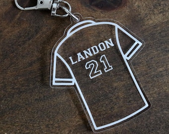 Può includere: Portachiavi in ​​acrilico bianco a forma di maglia con il nome Landon e il numero 21.