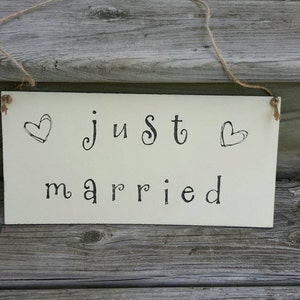 May include: A rustic off-white wooden sign with black lettering that says 