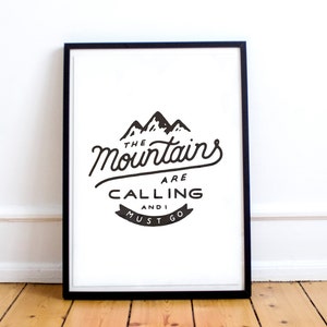 May include: Black and white print in a black frame with the text "The Mountains Are Calling And I Must Go". The print features a stylized image of three mountains.