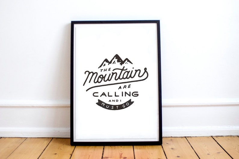 May include: Black and white print in a black frame with the text "The Mountains Are Calling And I Must Go". The print features a stylized image of three mountains.