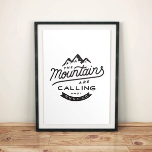May include: Black and white framed print with a mountain range graphic and the text "The Mountains Are Calling And I Must Go."