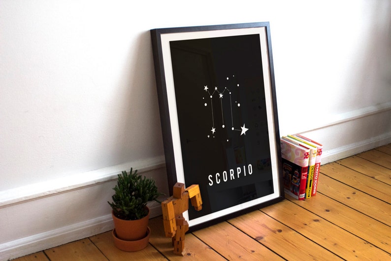 May include: A black framed print with a white constellation design of the Scorpio zodiac sign on a black background. The text "SCORPIO" is printed in white at the bottom of the print.