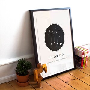 May include: Black framed print with a white background and a black circle containing a white constellation of stars. The text "Scorpio" is below the circle with the text "Passionate | Charismatic | Dynamic" below that.