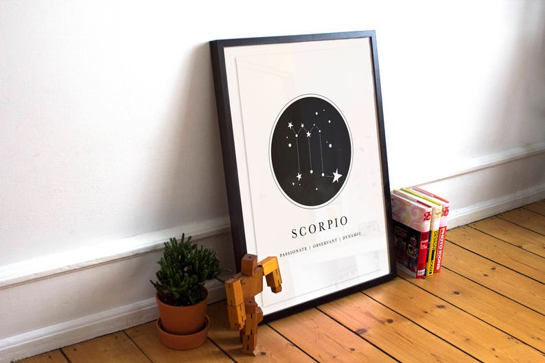 May include: Black framed print with a white background and a black circle containing a white constellation of stars. The text "Scorpio" is below the circle with the text "Passionate | Charismatic | Dynamic" below that.