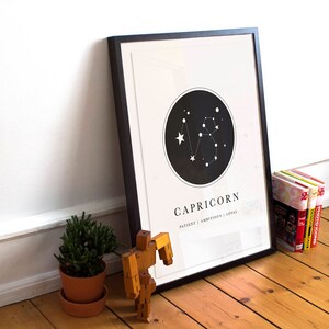 May include: A black framed print with a white background and a black circle containing a constellation of white stars. The text "CAPRICORN" is below the circle, with the words "PATIENT | AMBITIOUS | LOYAL" underneath.
