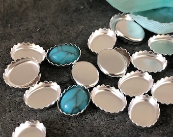 May include: A close-up of a group of silver-colored metal settings with a scalloped edge. Two of the settings have turquoise cabochons in the center.