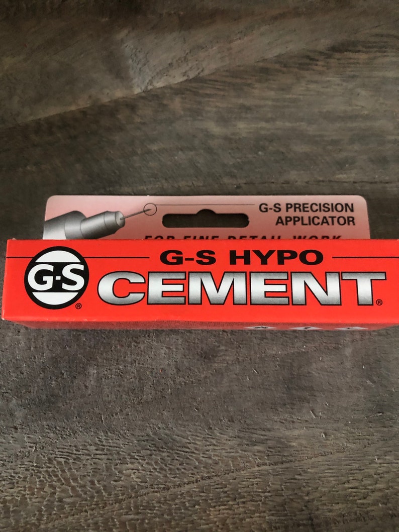 Op de afbeelding: Een rode tube G-S Hypo Cement met een wit label en een zwart-wit logo. Het label zegt "G-S Hypo Cement" en "G-S Precision Applicator".