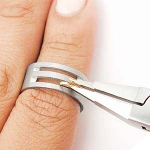 May include: A pair of silver ring mandrel pliers are used to resize a silver ring with three vertical lines cut into the band.