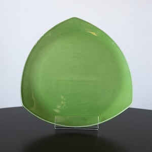 May include: A green triangular ceramic serving plate. The plate has a smooth, glossy finish.