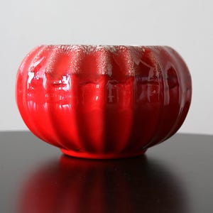 Puede incluir: Un cuenco de cerámica rojo brillante con un exterior acanalado. El cuenco tiene forma redondeada y una amplia abertura. El interior es de un tono rojo más claro. Este cuenco decorativo es adecuado para la decoración del hogar.