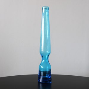 May include: A tall, slender glass vase with a light blue to dark blue gradient. The vase has a wide mouth and a narrow base.