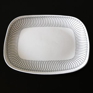 Può includere: Piatto da portata ovale bianco con un motivo geometrico nero e grigio attorno al bordo.