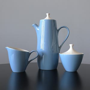 Może przedstawiać: Jasnoniebieski ceramiczny zestaw do kawy z kremową pokrywką i wnętrzem. Zestaw zawiera dzbanek do kawy, śmietankę i cukiernicę, wszystkie z błyszczącym wykończeniem. Dzbanek do kawy ma około 25 cm wysokości.