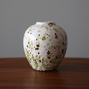 May include: White ceramic vase with a speckled brown and green glaze.