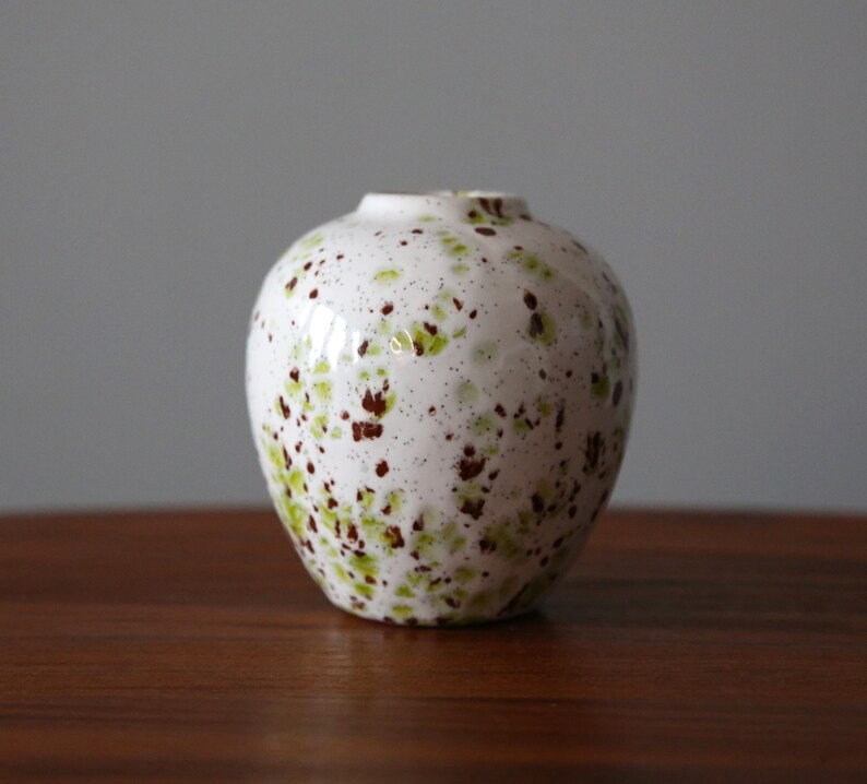 May include: White ceramic vase with a speckled brown and green glaze.