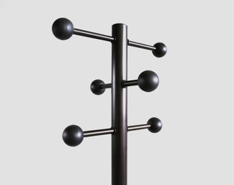 May include: A dark brown coat rack featuring a central vertical pole with six horizontal arms extending outward. Each arm terminates in a large, smooth, spherical ball end, providing a functional structure for hanging various items.