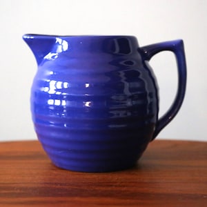 May include: A blue ceramic jug with a ribbed design. The jug has a rounded body and a handle.