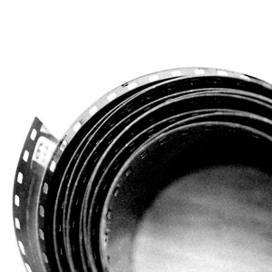 Könnte beinhalten: Eine Rolle Schwarzweißfilm ist fest gewickelt und zeigt die Perforationen und die Textur des Films.