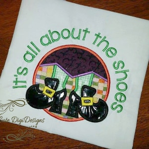 May include: White t-shirt with green embroidery that reads "It's all about the shoes". The embroidery includes two black witch shoes with green buckles and a purple and green background.