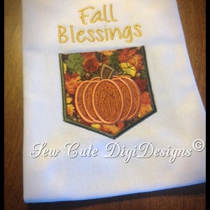 May include: White kitchen towel with embroidered text "Fall Blessings" and a pumpkin with fall leaves in a pocket design. The text "Sew Cute Digi Designs" is embroidered at the bottom.