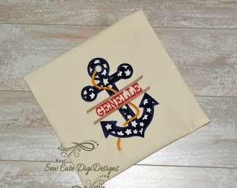 May include: A white fabric with a blue and white anchor with stars and a red and white rope. The name "GENELLE" is written across the anchor in red.