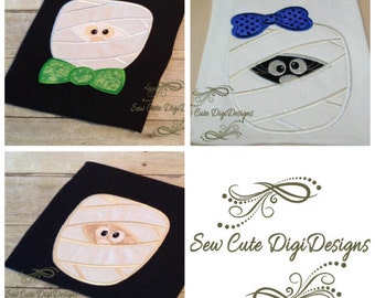 May include: Three embroidery designs of a mummy with a bow tie, a mummy with a bow, and a mummy with eyes peeking out. The designs are on black and white fabric. The text "Sew Cute Digi Designs" is in the center of the image.