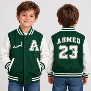May include: A dark green and white varsity jacket featuring a snap-button front, striped ribbed collar, cuffs, and hem. The front displays the letter A and Arabic text, while the back features the name AHMED and the number 23 in white lettering.