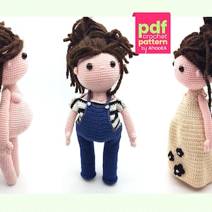May include: Three crochet dolls with brown yarn hair and black eyes. One doll is wearing blue overalls, another a beige dress with black flower accents, and the third is nude. The dolls are handmade and appear to be part of a crochet pattern.