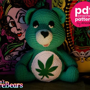 May include: Green crocheted Care Bear with a white marijuana leaf on its chest. The bear is sitting on a table with a colorful background. The text "Don't Care Bears" is visible in the bottom left corner of the image.
