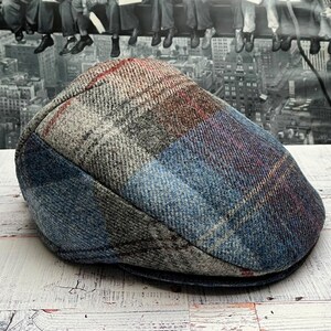 May include: A blue, gray, and red plaid wool flat cap. The cap has a slightly curved brim and a soft, comfortable feel.