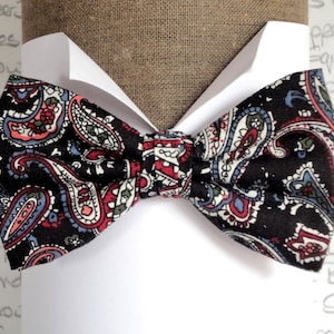 Op de afbeelding: Een zwarte strik met een paisley-patroon in tinten rood, blauw en wit.