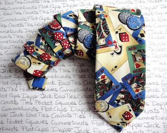 May include: A silk necktie with a cream background and a colorful pattern of playing cards, dice, and poker chips. The tie features a variety of card suits, including hearts, spades, diamonds, and clubs.