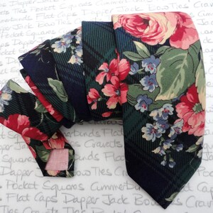 May include: A dark blue and green patterned tie with a floral design. The tie features pink, blue, and white flowers on a dark background.