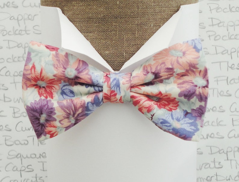 May include: A floral patterned bow tie with pink, red, purple, and blue flowers on a white background.