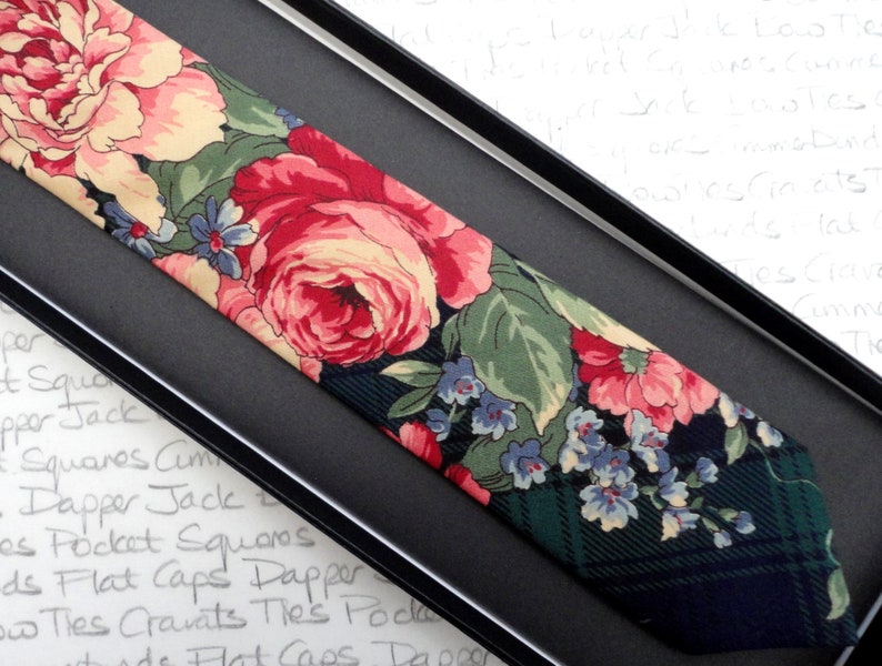 May include: A dark green and black patterned tie with a floral design featuring pink, red, and white roses and blue flowers.
