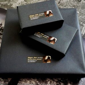 May include: Three black boxes with gold lettering and a logo of a bow tie. The text on the boxes reads "Dapper Jack Hand Crafted Bow Ties".