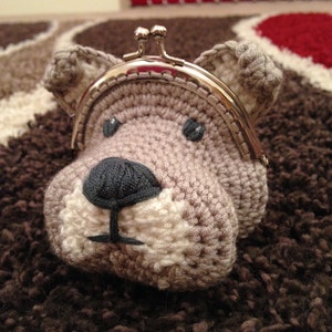 Puede incluir: Una cartera de monedas de crochet en forma de perro gris y blanco con un marco de metal plateado.