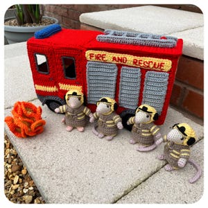 以下が含まれることがあります： 「FIRE AND RESCUE」の文字が入った赤い手編みの消防車。消防士に扮した4匹の編みぐるみネズミと、編みぐるみの炎も含まれています。手作りの楽しいおもちゃです。