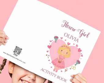 Peut inclure: Un livre d'activités rose et blanc avec le texte "Flower Girl OLIVIA ACTIVITY BOOK". La couverture présente une fille de dessin animé en robe rose à l'intérieur d'un cœur rose avec des fleurs et des flèches.