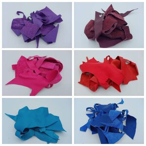 Op de afbeelding: Assortiment van lederen restjes in verschillende kleuren, waaronder paars, bordeauxrood, roze, blauw en turquoise. De restjes zijn in stapels op een witte achtergrond gerangschikt.
