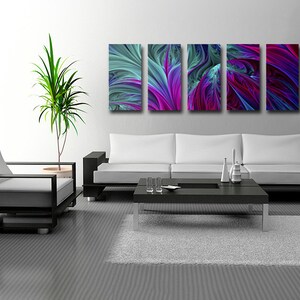 Może przedstawiać: Nowoczesne wnętrze salonu z białą sofą, czarnym stolikiem kawowym i szarym dywanem. Na ścianie znajduje się zestaw pięciu abstrakcyjnych grafik w odcieniach niebieskiego, fioletowego i zielonego.