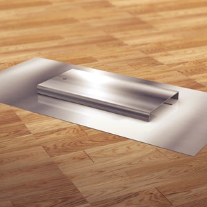 May include: A silver metal rectangular box sits on a silver metal surface. The surface is on a wooden floor.