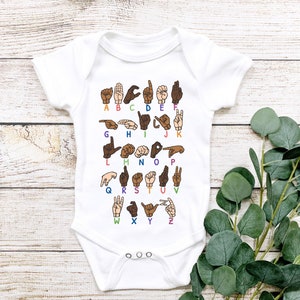 May include: White baby bodysuit with a colourful American Sign Language (ASL) alphabet design. Each letter is shown as a hand gesture in different skin tones. The letters are arranged in rows, making it easy to learn the ASL alphabet.
